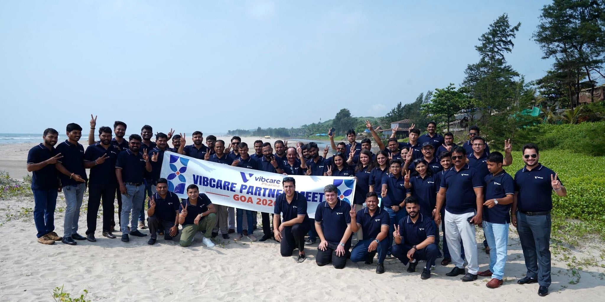 Vibcare partners and team with the Partner Meet banner on Mandrem beach, Goa